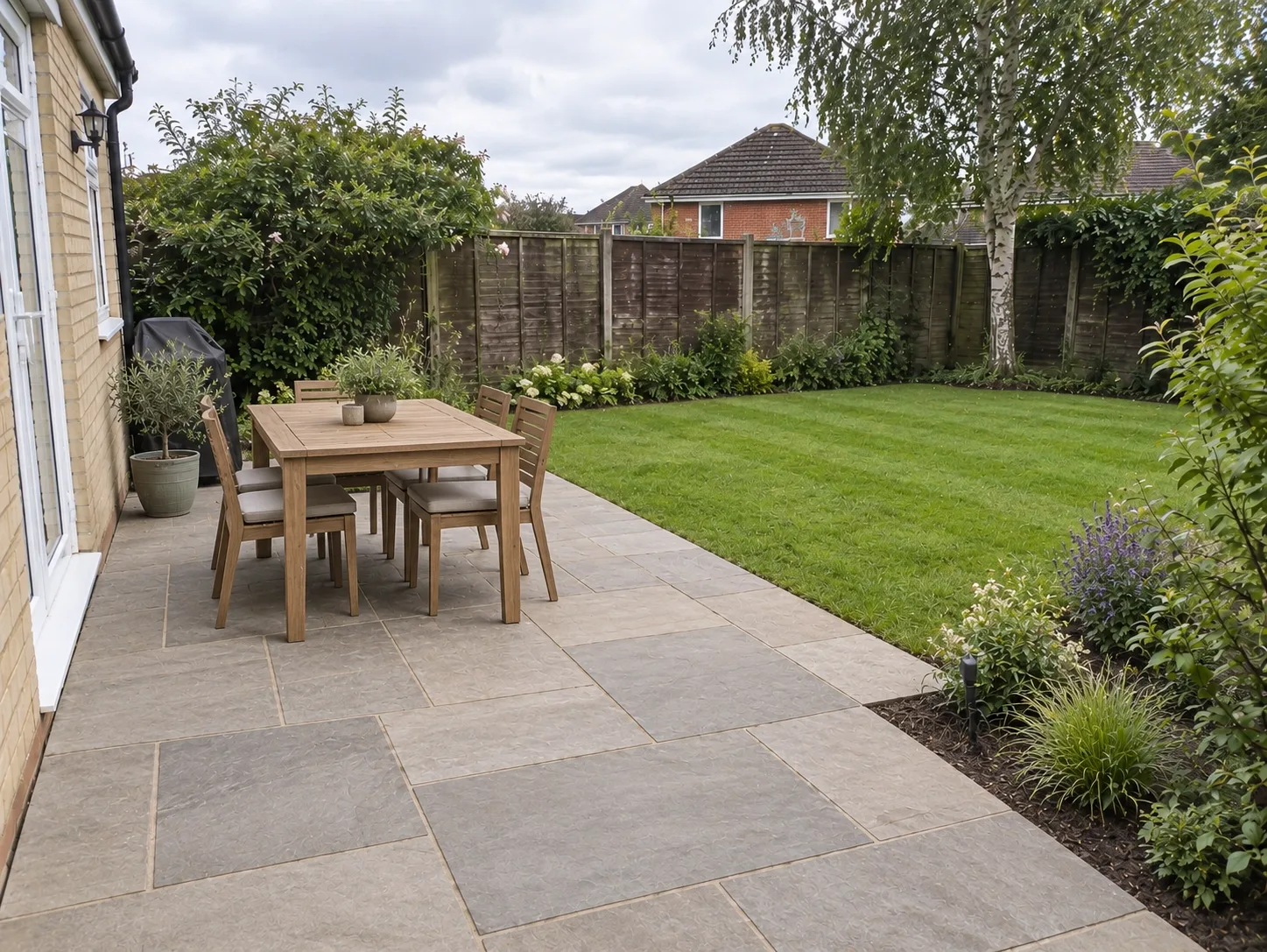 Example patio with a table and chairs beside a lawn.